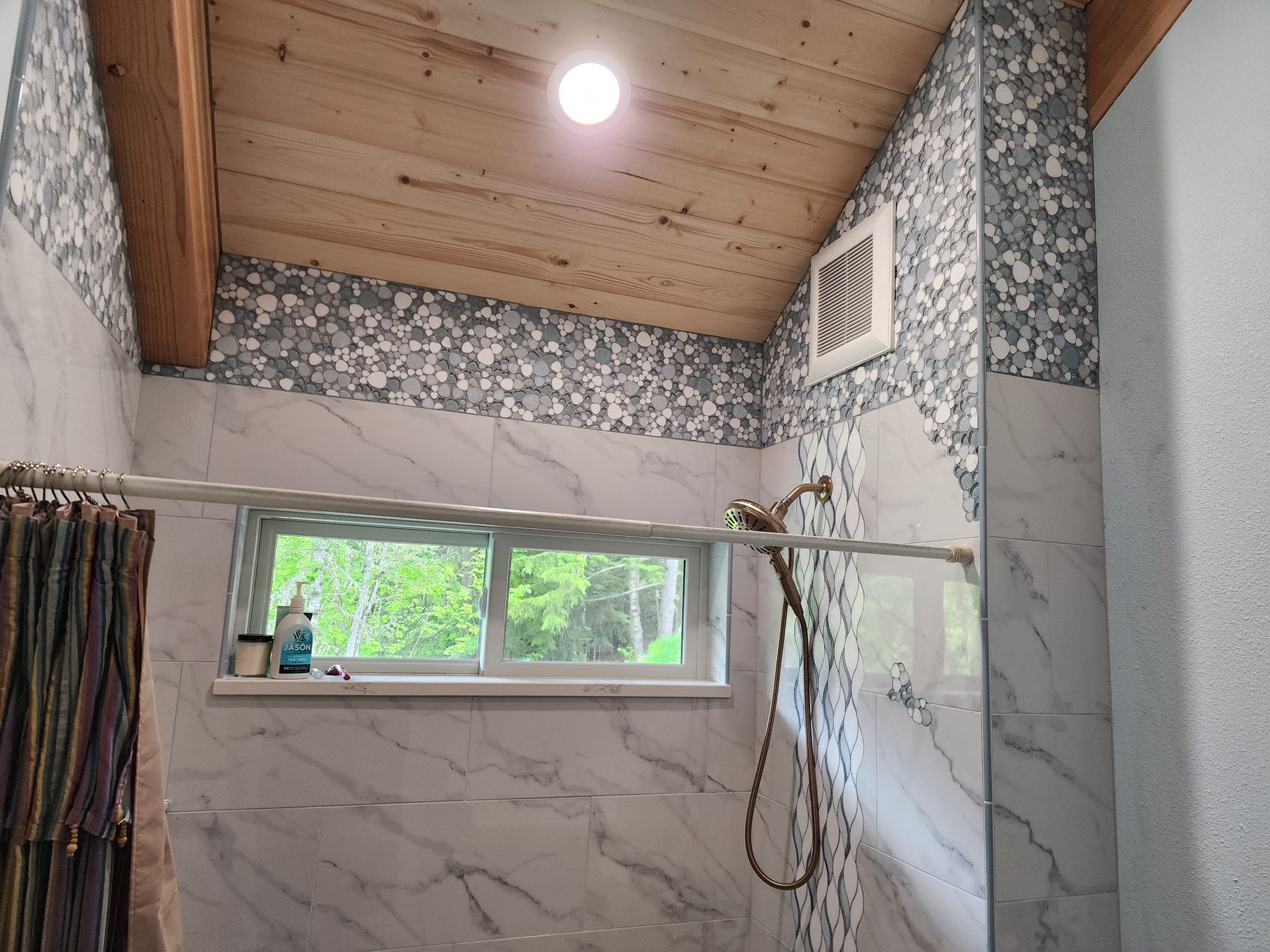 Marble-look tile tub and shower surround with pebble mosaic accent band