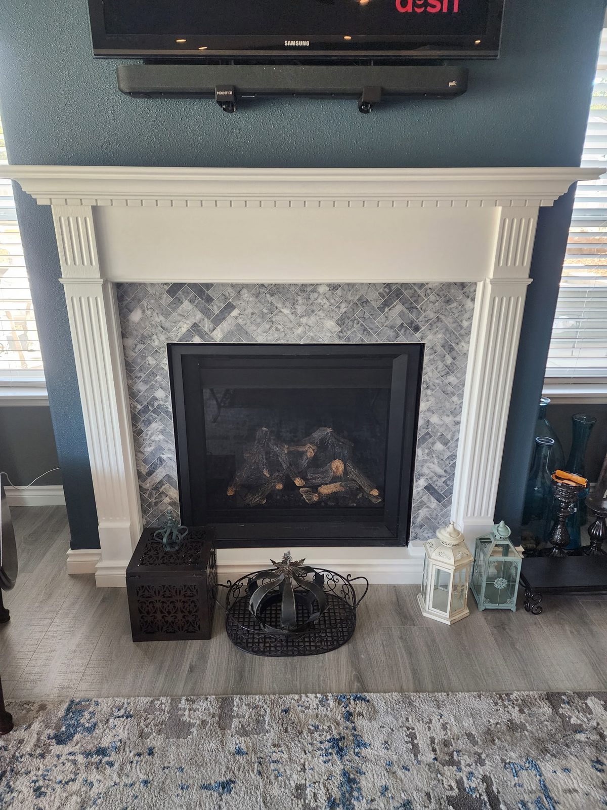 White painted mantel with gray herringbone tile surround and gas fireplace insert