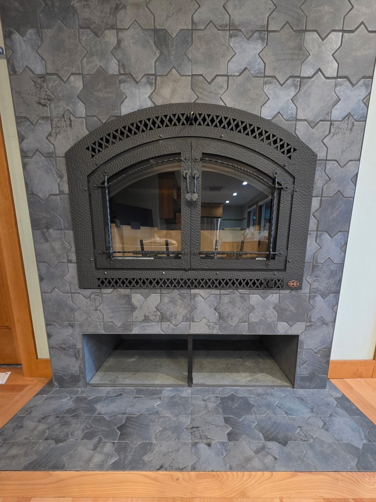 Gray star-and-cross Moroccan tile fireplace with arched iron doors and hearth