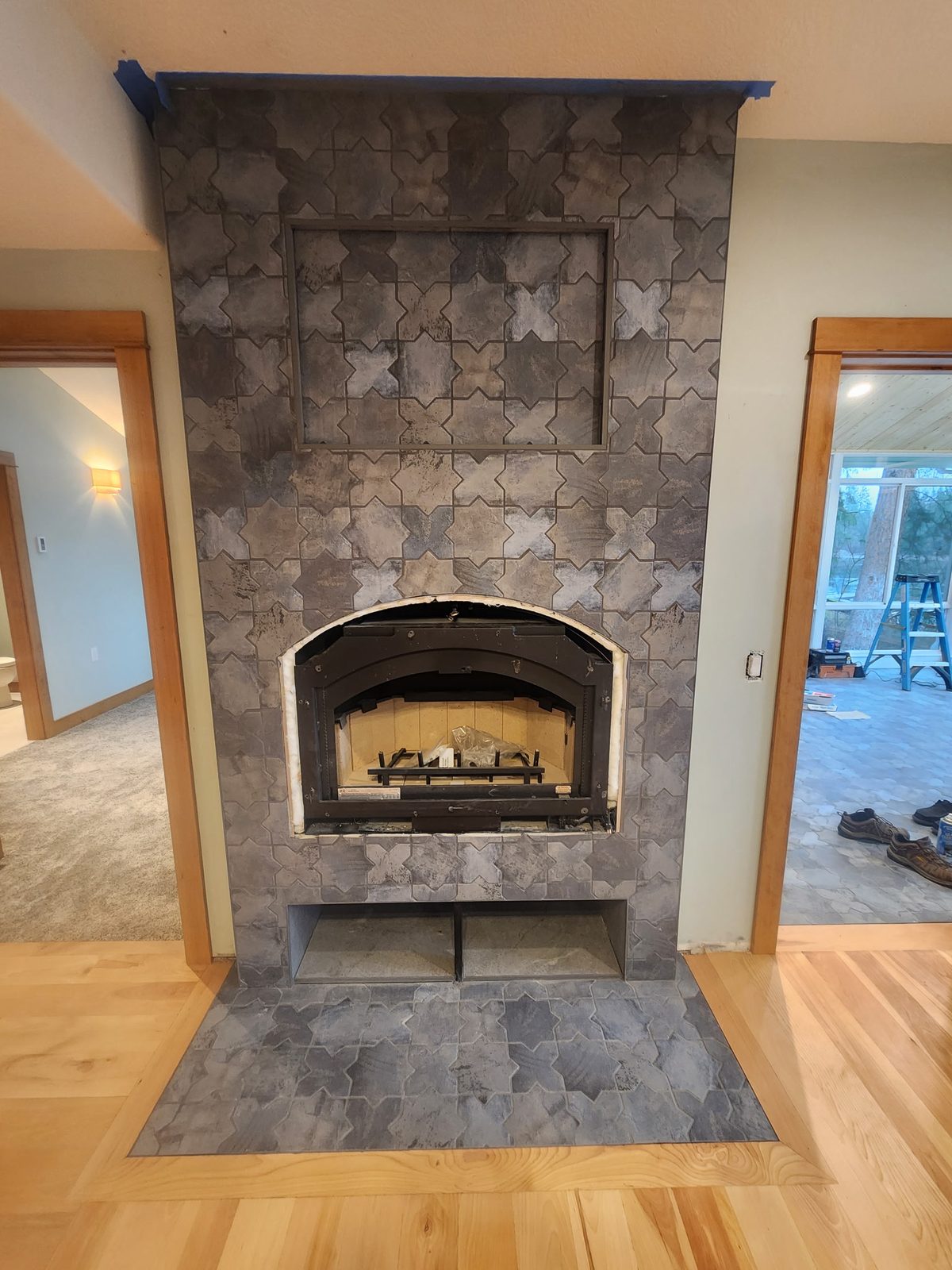 Floor-to-ceiling gray star-and-cross tile fireplace with raised hearth