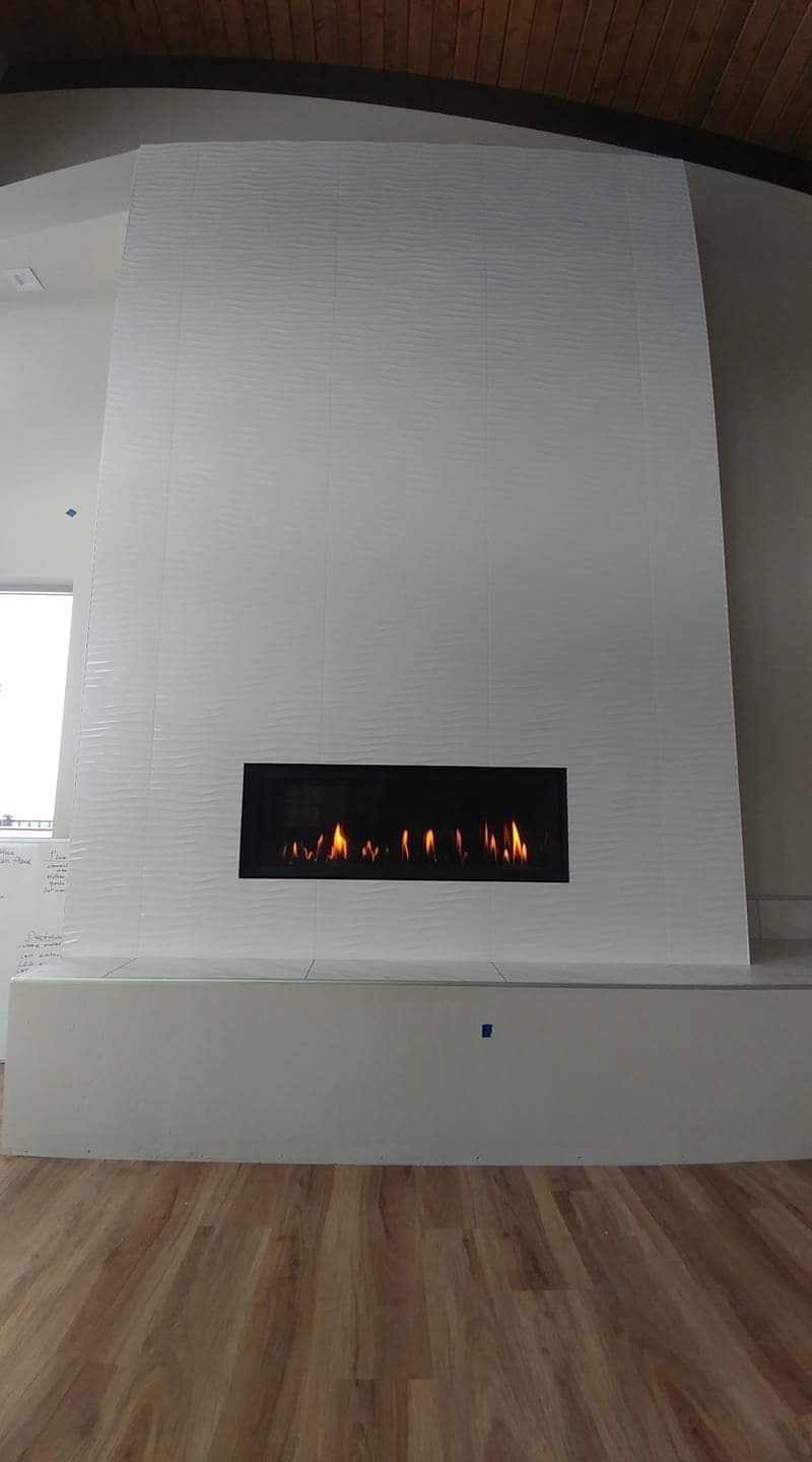 Floor-to-ceiling white textured tile wall with linear gas fireplace