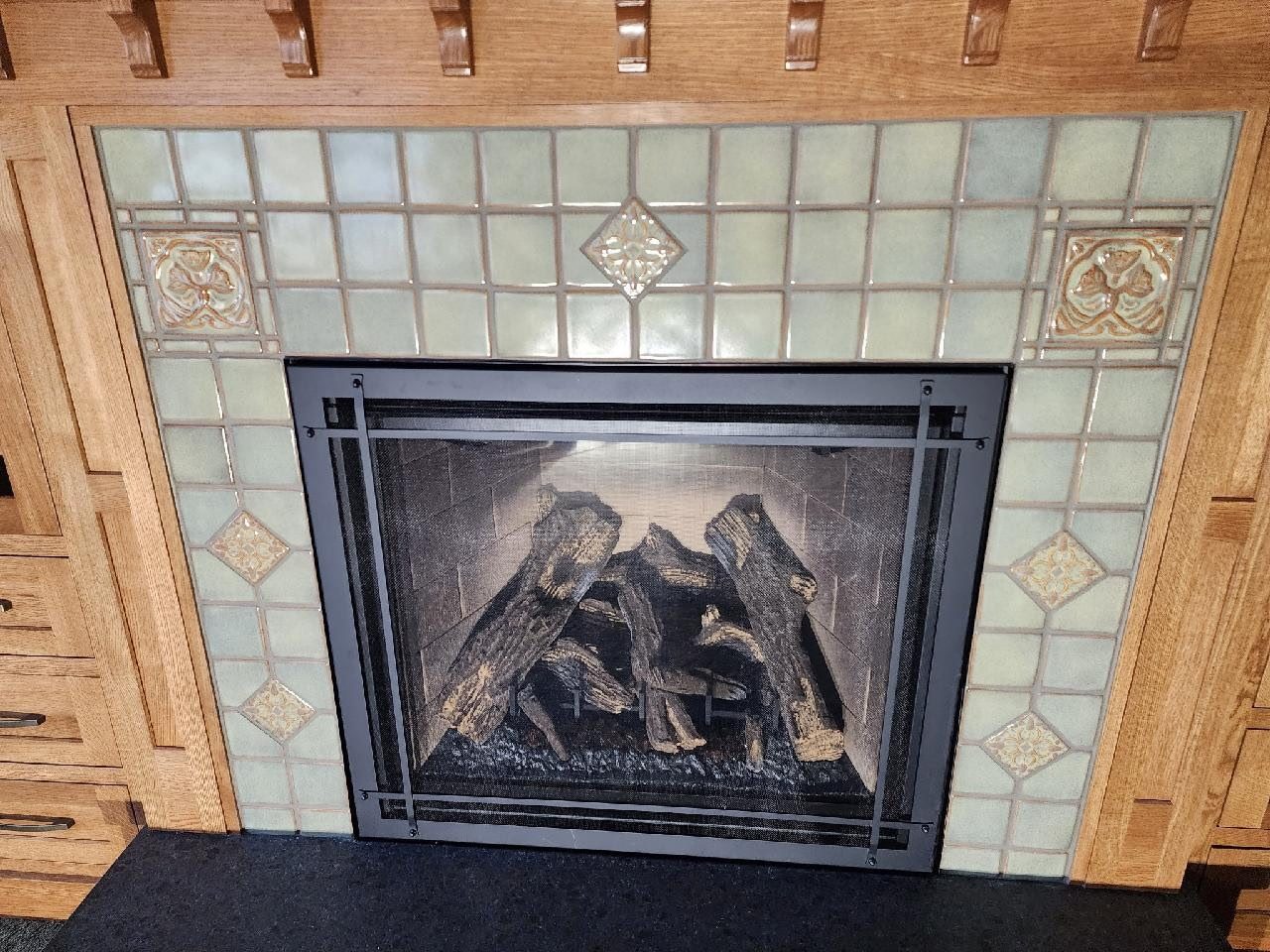 Green art-tile fireplace surround with oak mantel and gas logs