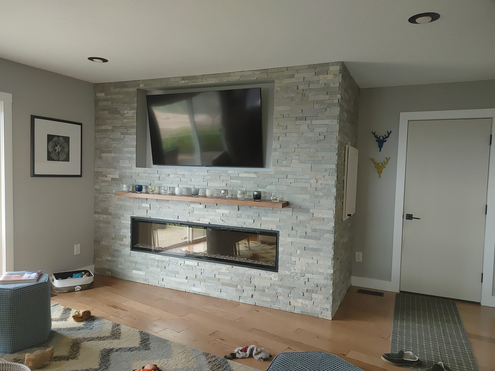 Light gray stacked-stone feature wall with see-through linear fireplace and mounted TV