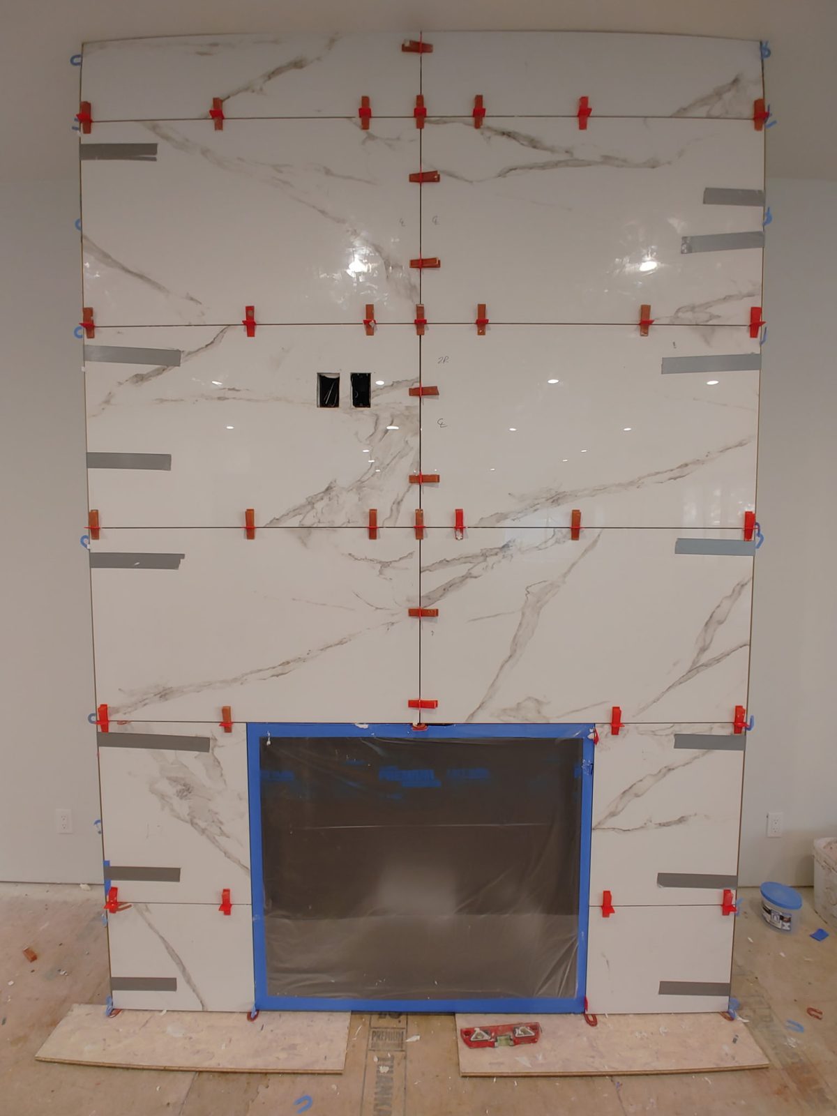 White marble-look porcelain slab fireplace surround during installation