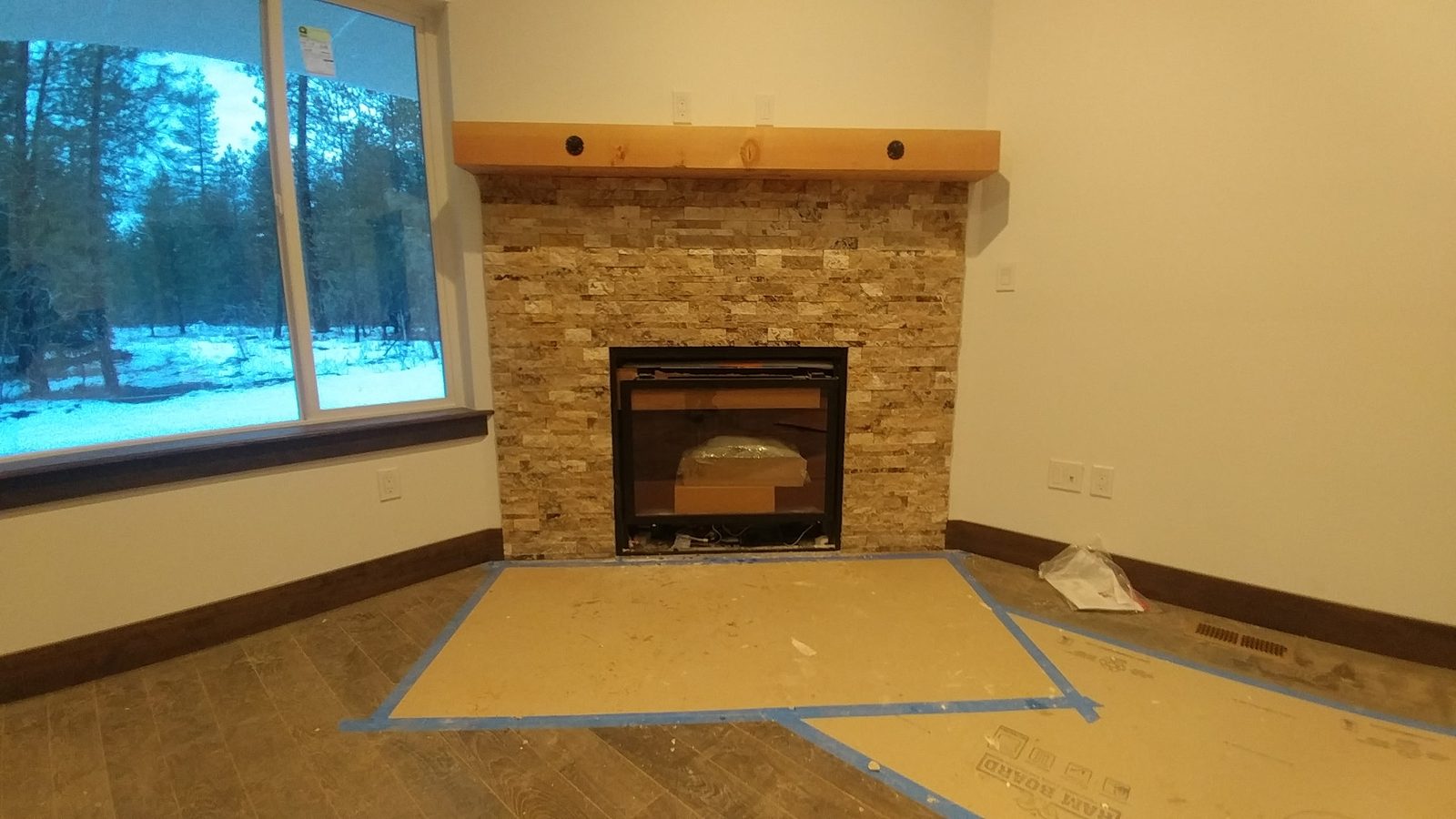 Travertine split-face stone fireplace surround with wood mantel