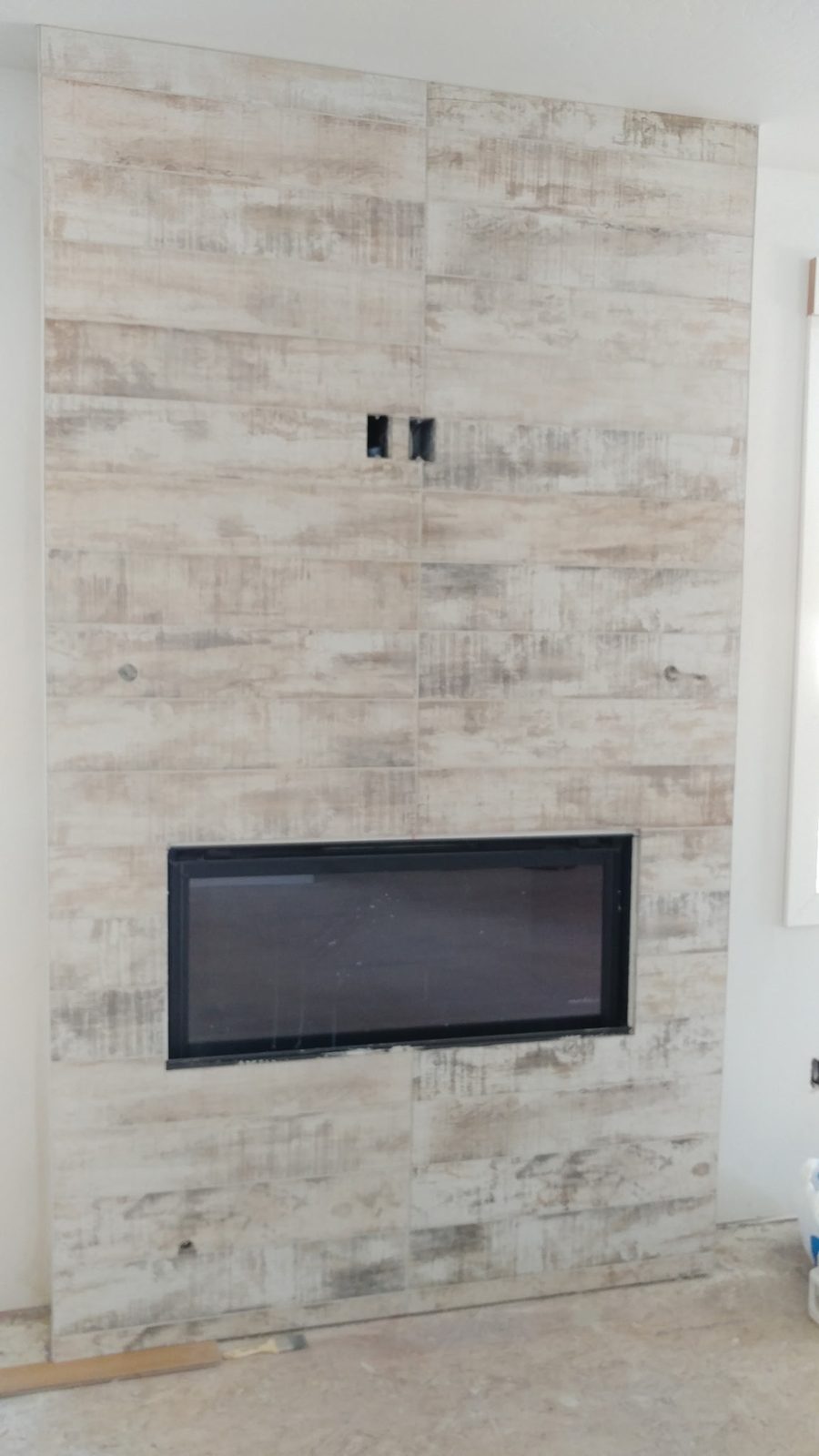 Whitewashed weathered-wood-look tile fireplace wall with linear gas fireplace