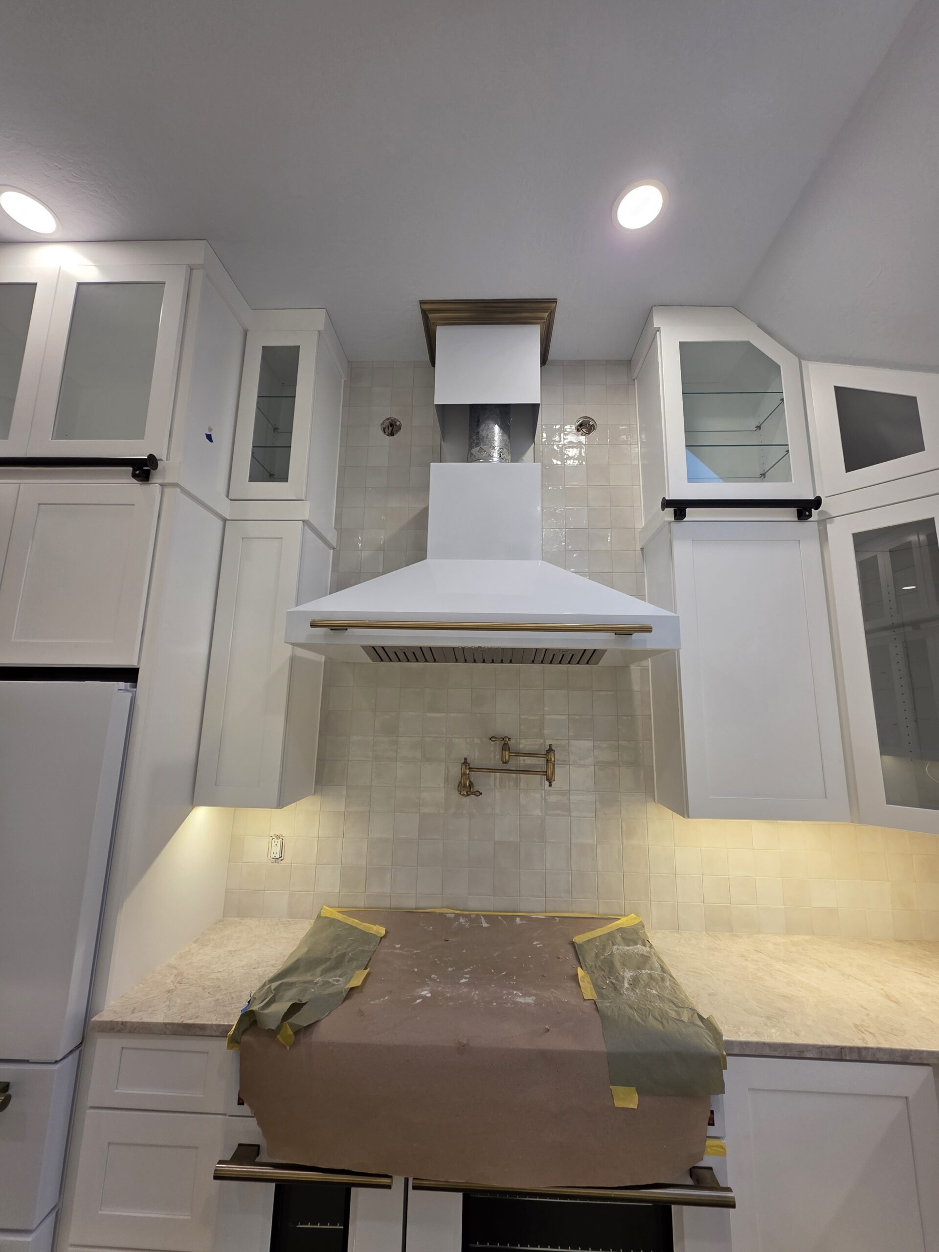 Kitchen stove area with vent hood and tile backsplash