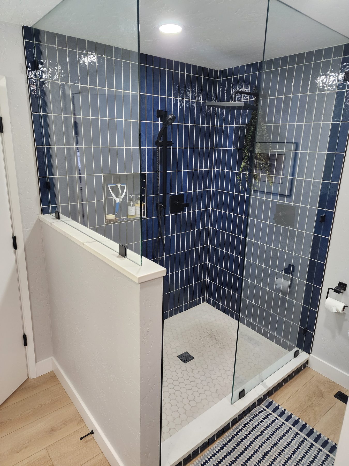 Navy blue tile walk-in shower with frameless glass enclosure