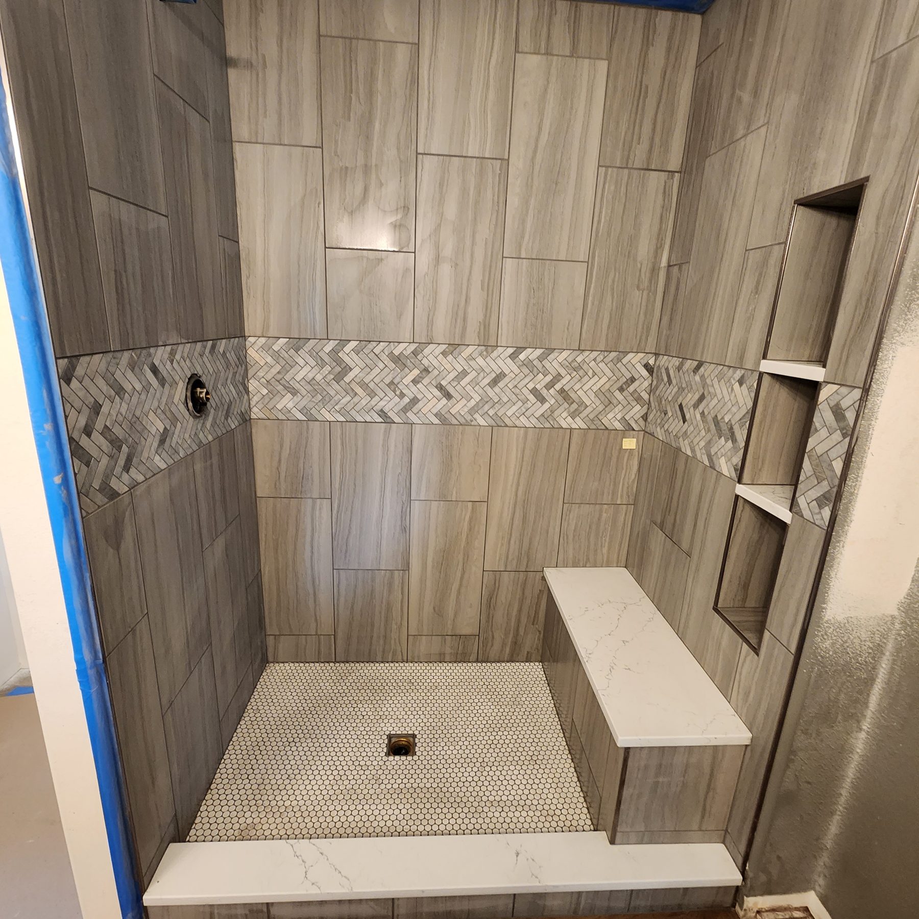 Walk-in shower with wood-look plank tile and herringbone accent band