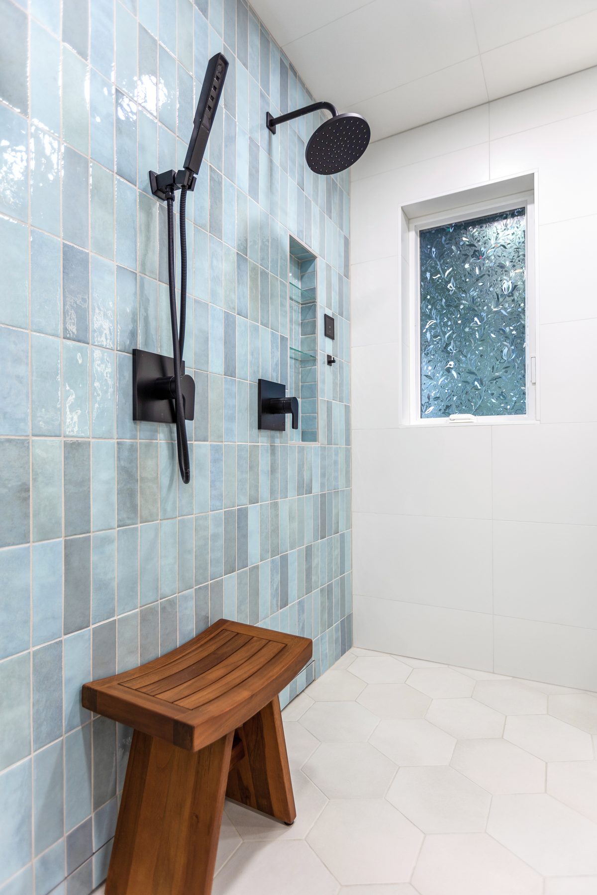 Walk-in shower with seafoam tile, teak bench and matte black fixtures