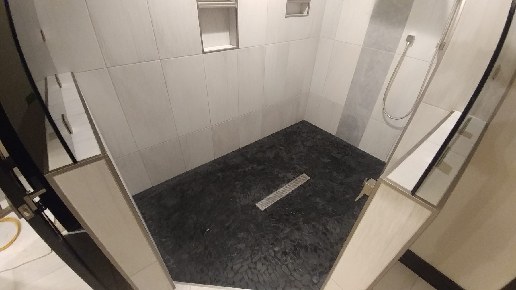 Walk-in shower with linear drain and dark stone shower pan